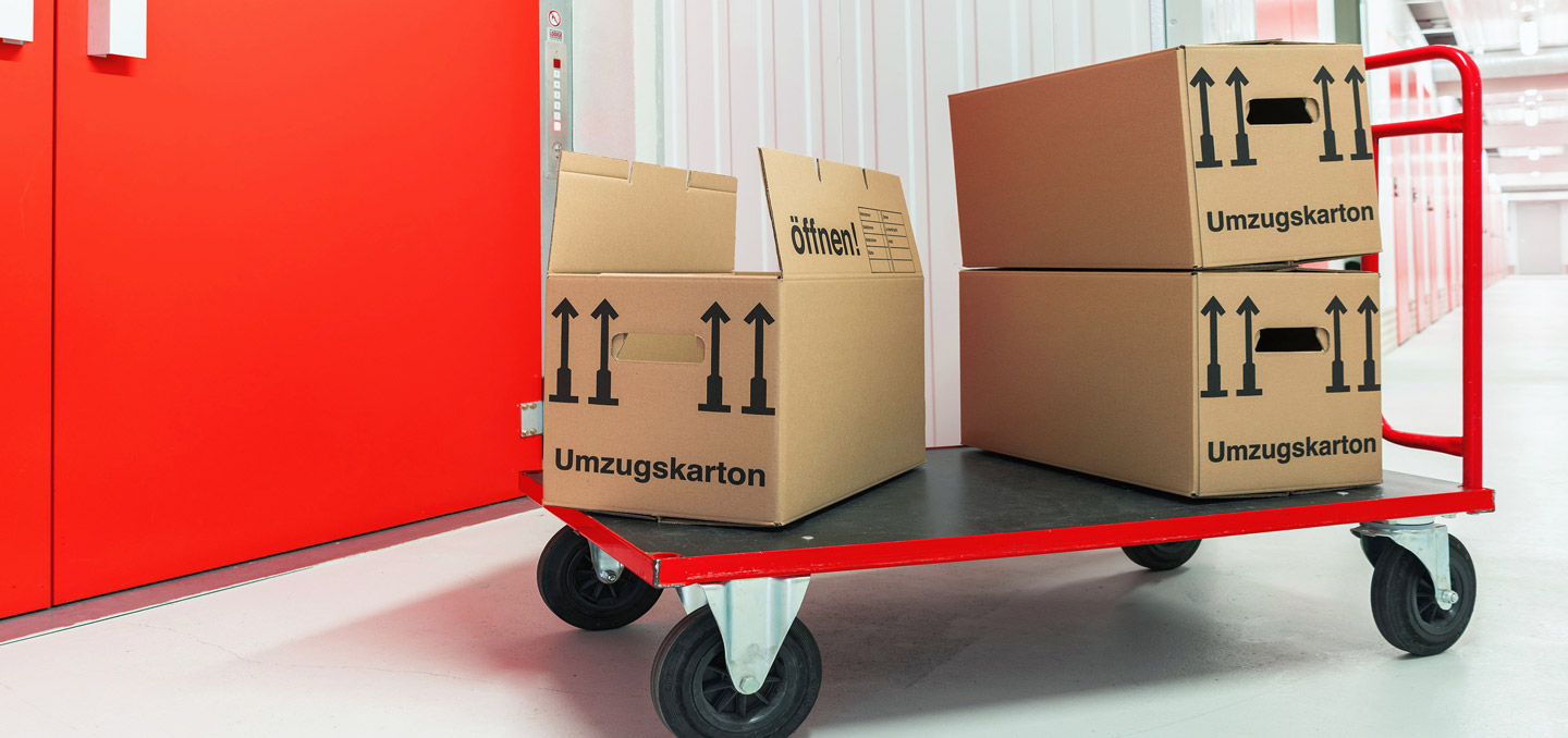 Rollwagen mit Umzugskartons vor Lagerraum