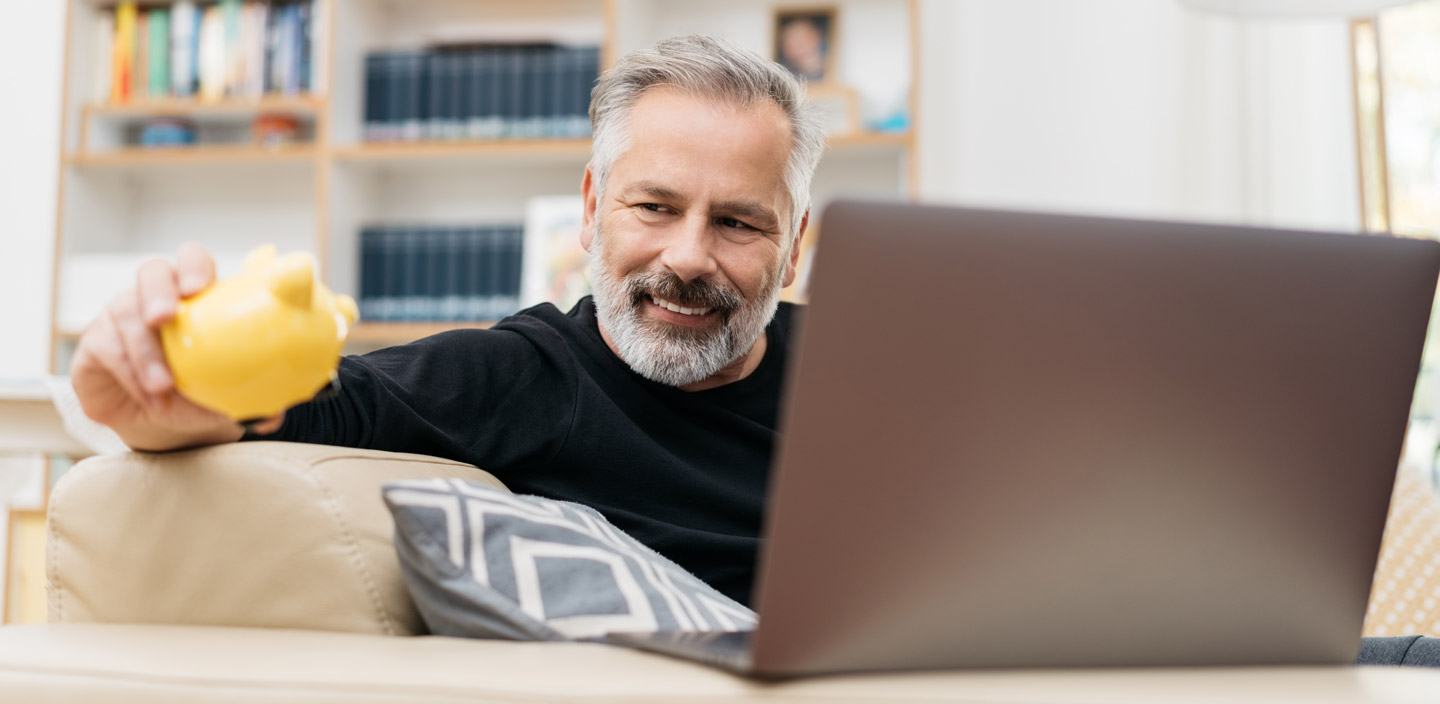 Mann schaut auf sein Sparschwein